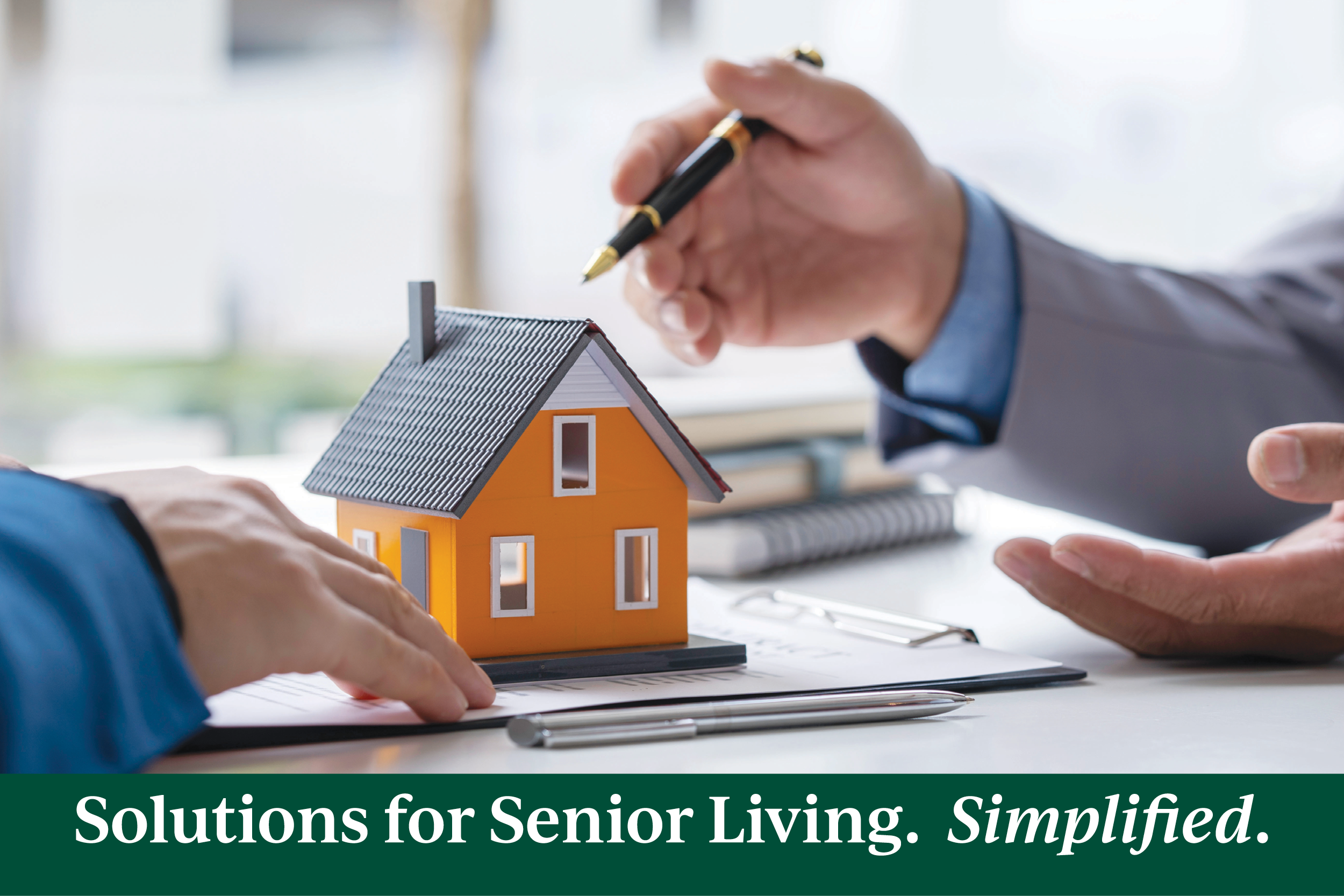 A model house is on the table as two people converse about it.